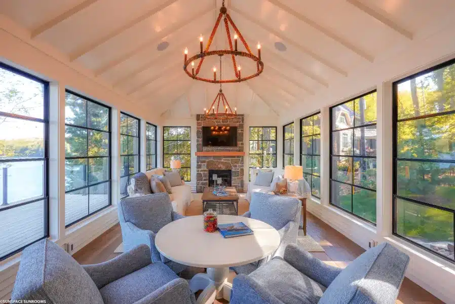 A sun-drenched sunroom with white-framed WeatherMaster™ windows, a vaulted ceiling, a banana leaf area rug, and a wooden bench.