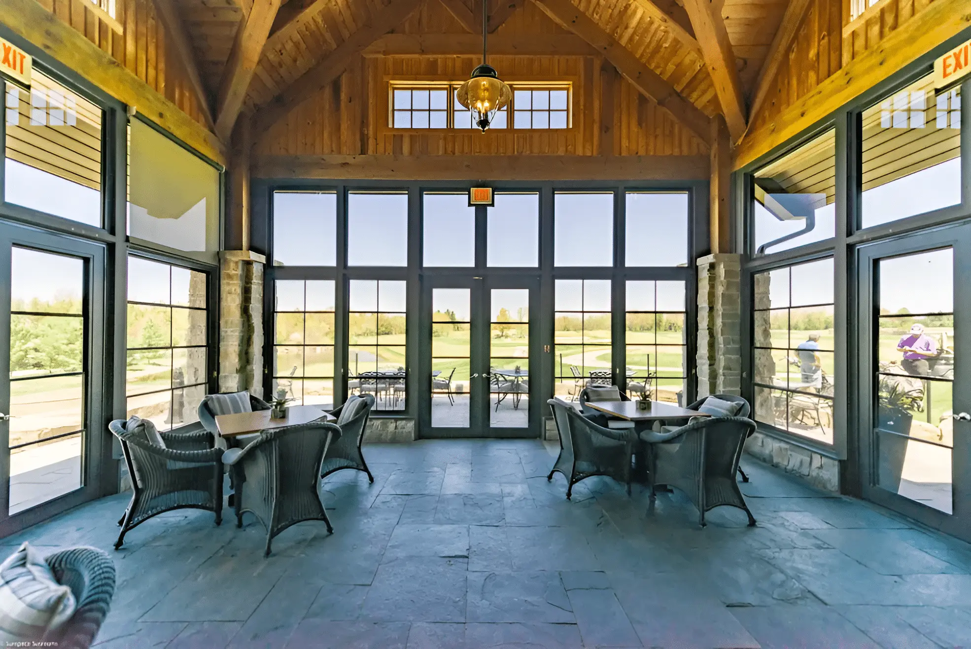 A large timber-frame sunroom with slate floors and WeatherMaster™ vertical 4-track windows overlooking a golf course.